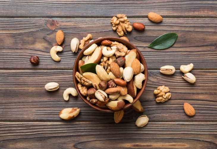 A wooden bowl filled with nuts on top of a wooden table