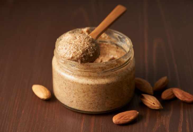 A jar of almond nut butter with a wooden spoon