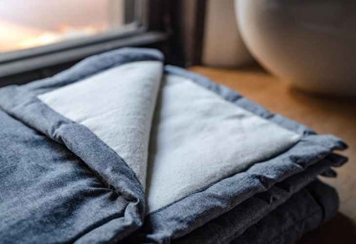 A folded blankets sitting next to a window