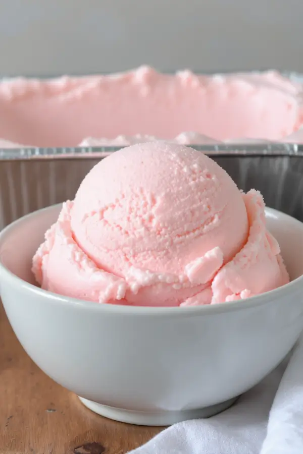 One loaf pans filled with creamy no‑churn ice cream with a smooth surface, scoops of ice cream served in a bowl