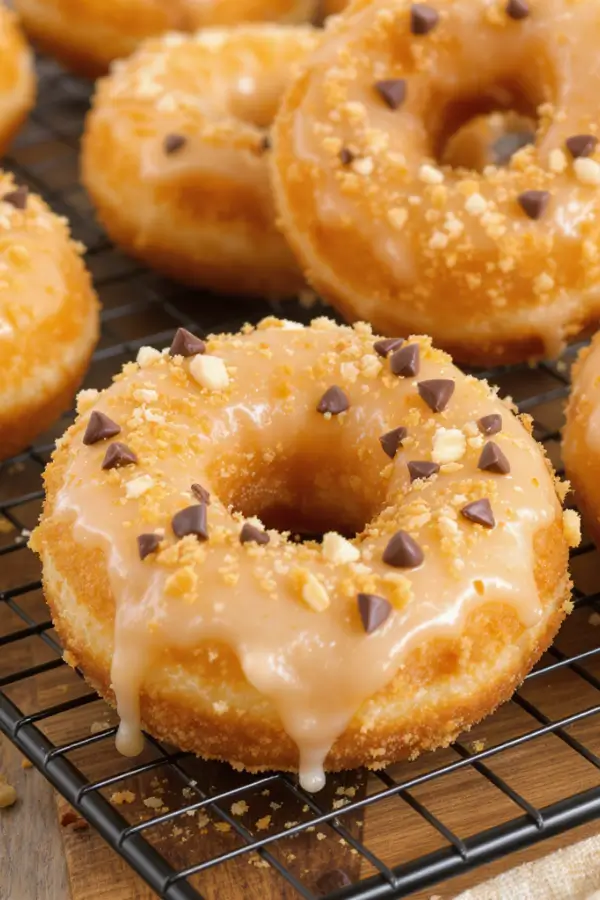 Golden, fluffy air‑fried donuts with a light glaze, sprinkled with crushed nuts and sugar‑free chocolate chips, arranged on a cooling rack