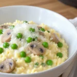 A creamy Instant Pot risotto served in a bowl, topped with freshly grated Parmesan, and scattered with tender mushrooms and peas on the kitchen countertop