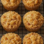 Golden apple cinnamon muffins with crumbly streusel topping, arranged on a cooling rack