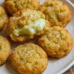 A plate of golden brown pistachio cookies, sprinkled with flaky sea salt, soft centers with a hint of green from pistachio cream