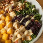 fall harvest bowl with golden roasted butternut squash, juicy seared chicken cubes, sautéed kale, dried cranberries, toasted pecans, and a drizzle of Dijon apple cider dressing, served in a ceramic bowl
