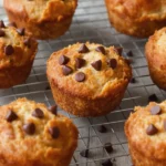 Golden mini banana bread loaves on a cooling rack, each studded with melted chocolate chips and sprinkled with extra chips on top, with a soft, moist crumb