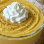 Creamy pumpkin cheesecake dip in a glass bowl, topped with cinnamon and dollops of whipped cream