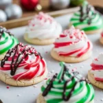 Christmas meringue cookies in white, red, and green swirls, topped with crushed candy canes, chocolate drizzle, and edible glitter, arranged on a parchment-lined baking sheet