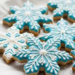 Snowflake sugar cookies with white and blue royal icing, sparkling sugar, arranged on parchment