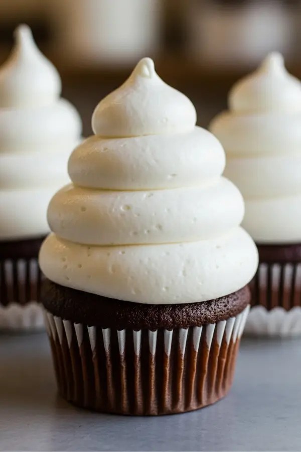 Fluffy white marshmallow frosting swirled tall on cupcakes