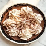 A whole chocolate cream pie in a white ceramic pie dish