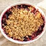 A freshly baked mixed berry crumble in a white ceramic baking dish