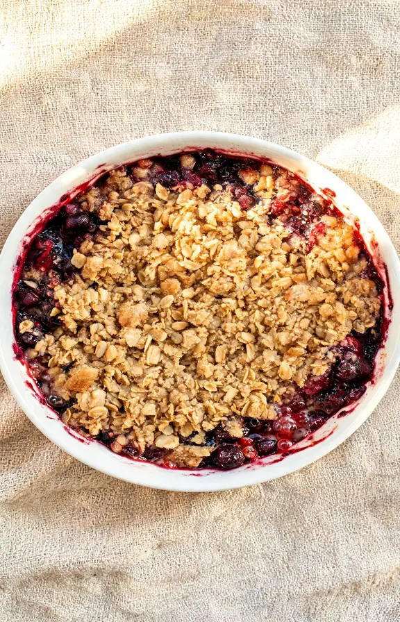A freshly baked mixed berry crumble in a white ceramic baking dish