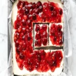 Close-up overhead shot of a white parchment-lined 8x8 pan filled with no bake cherry cheesecake bars