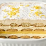 Lemon tiramisu in a white baking dish with clean-cut layers of mascarpone cream, lemon curd, and soaked ladyfingers