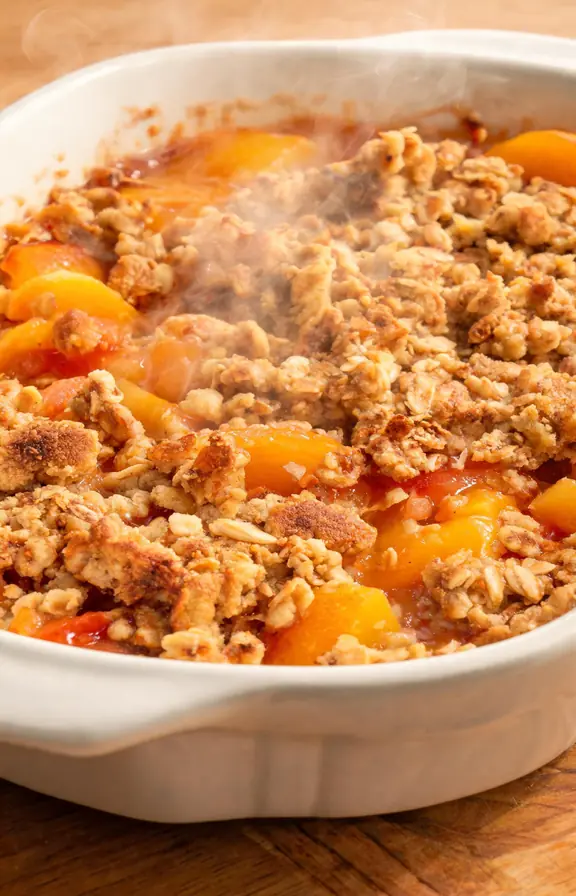 golden peach crisp with oat topping fresh from the oven in a baking dish
