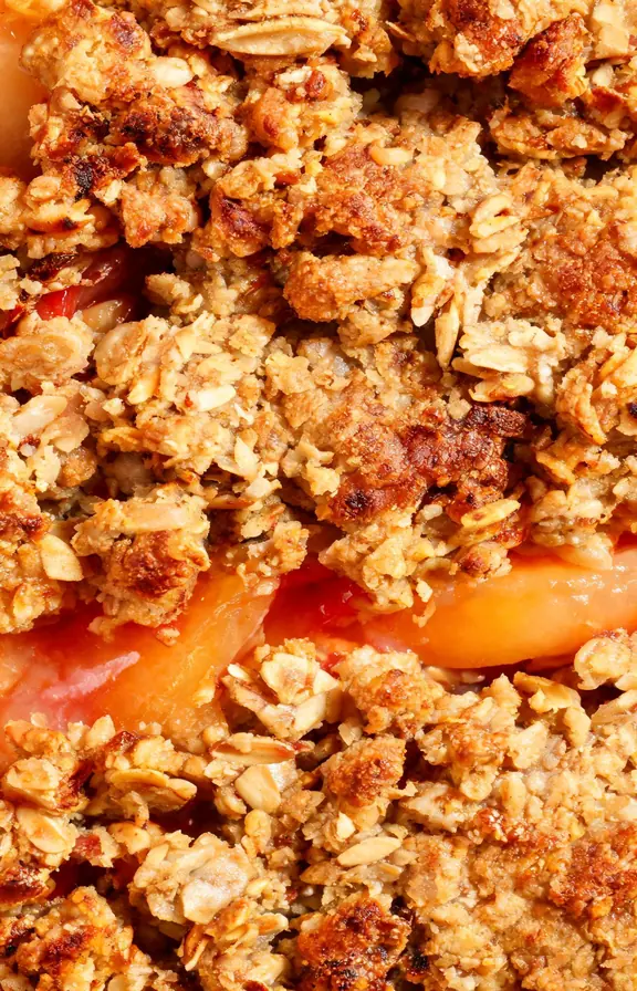 close up of golden oat topping on peach crisp showing crisp clusters