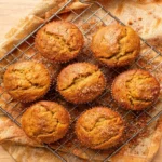 Stack of cinnamon sugar pumpkin muffins with a crackled sugar crust on a wire cooling rack