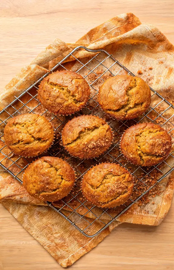 Stack of cinnamon sugar pumpkin muffins with a crackled sugar crust on a wire cooling rack