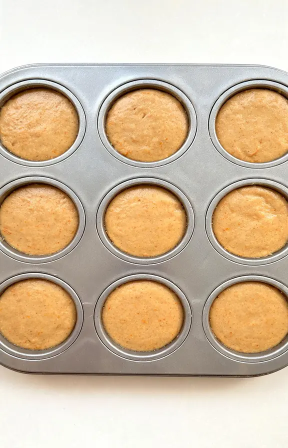 Pumpkin muffin batter filled to the top of a muffin tin before going into a hot oven