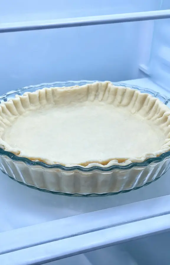 Unbaked pie crust fitted into a glass pie dish with a fluted edge, chilling before baking