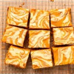 Overhead shot of sliced pumpkin cheesecake bars with a marbled swirl top on a wire rack
