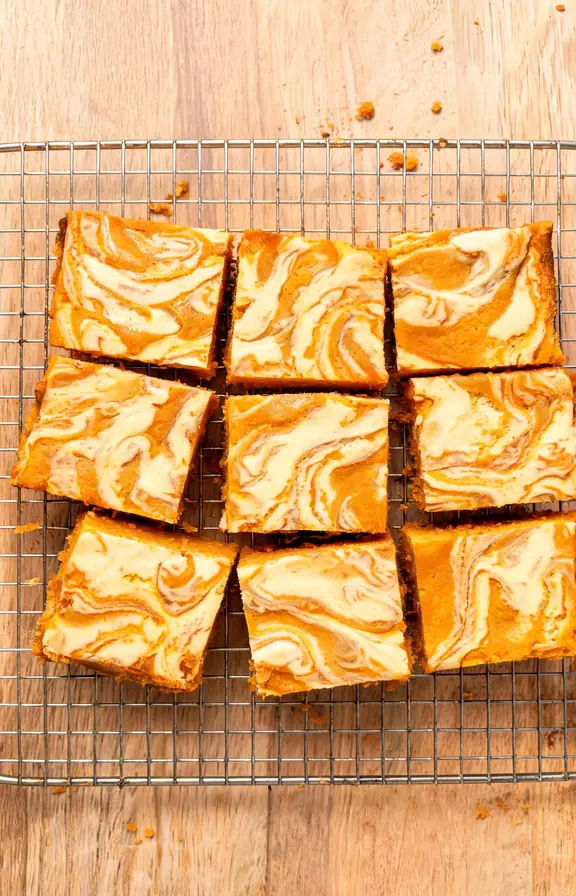 Overhead shot of sliced pumpkin cheesecake bars with a marbled swirl top on a wire rack