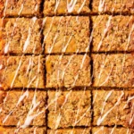 Sliced pumpkin coffee cake with brown sugar streusel topping and vanilla glaze on a white platter
