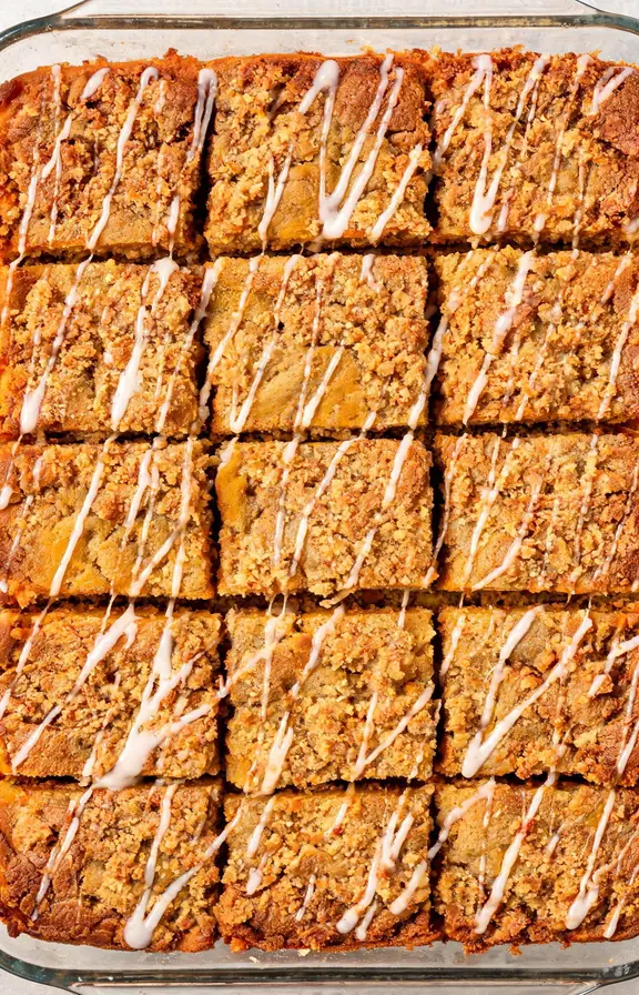 Sliced pumpkin coffee cake with brown sugar streusel topping and vanilla glaze on a white platter