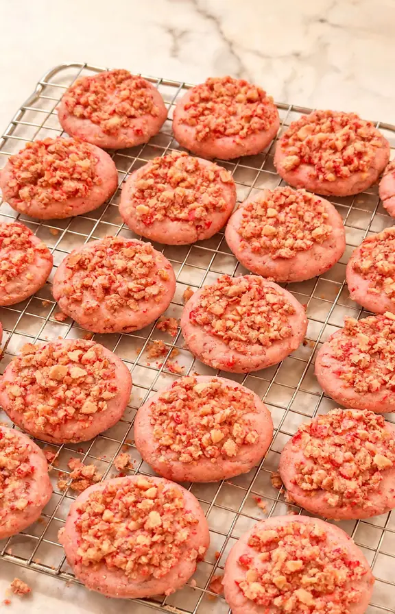 Baked strawberry crunch cookies on a cooling rack with golden crumb topping pressed into the tops